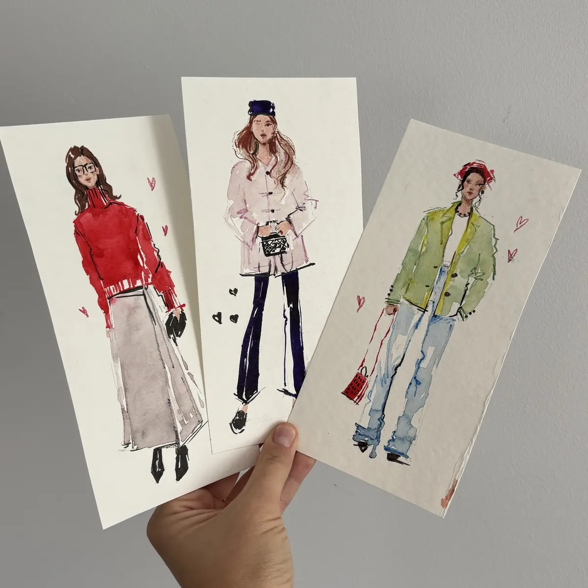Three live fashion sketches held in one hand