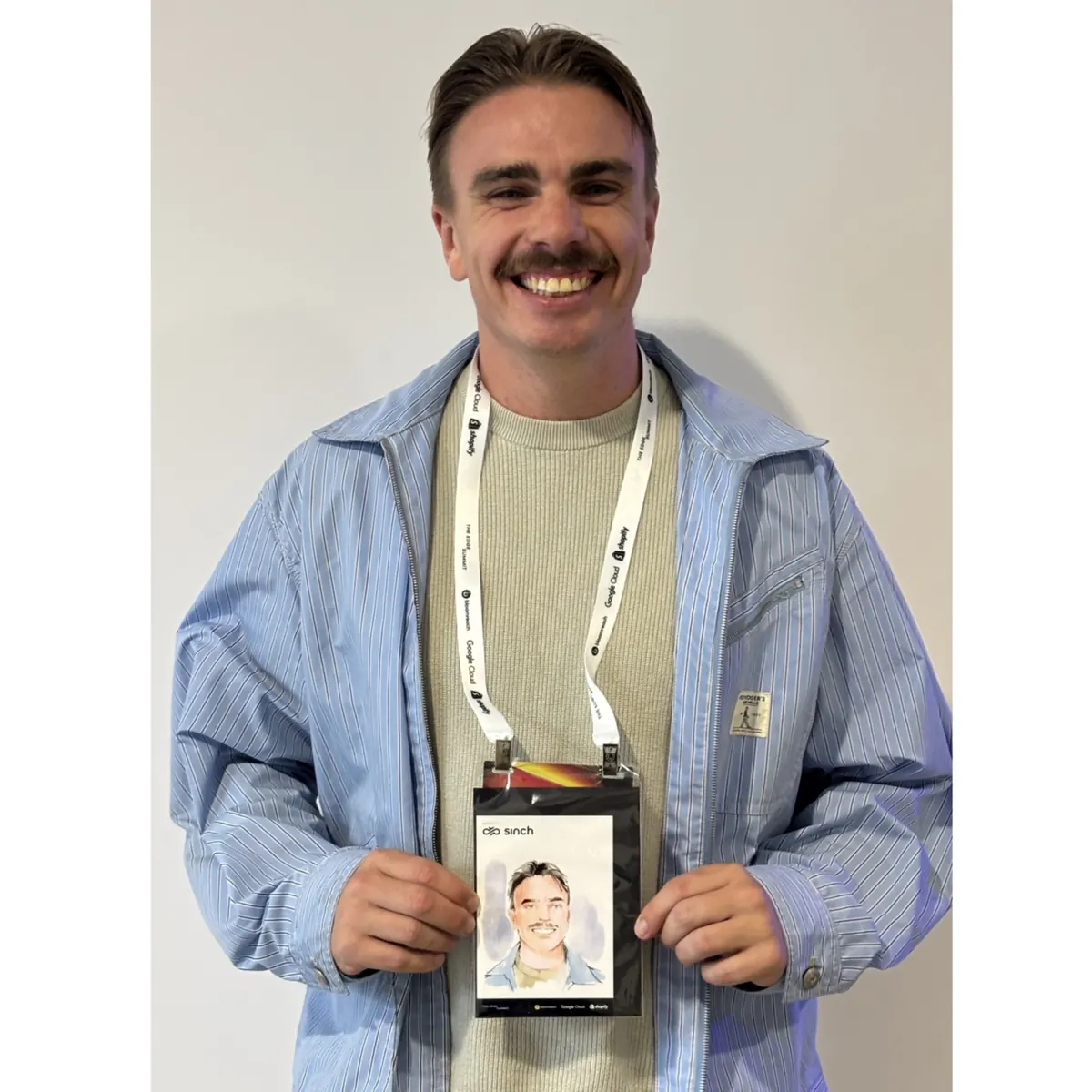 Guest with a conference lanyard holding his portrait
